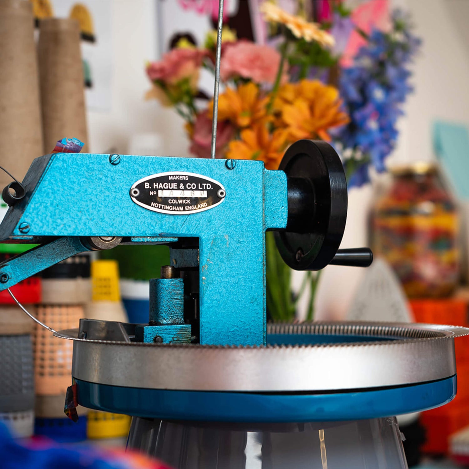 Blue metal linking machine in front of a colourful bunch of flowers.