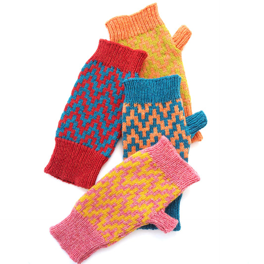 A colourful pile of single fingerless gloves by K.Moods. They have a thick zig-zag pattern, and are red, blue, yellow, green, orange, and pink.