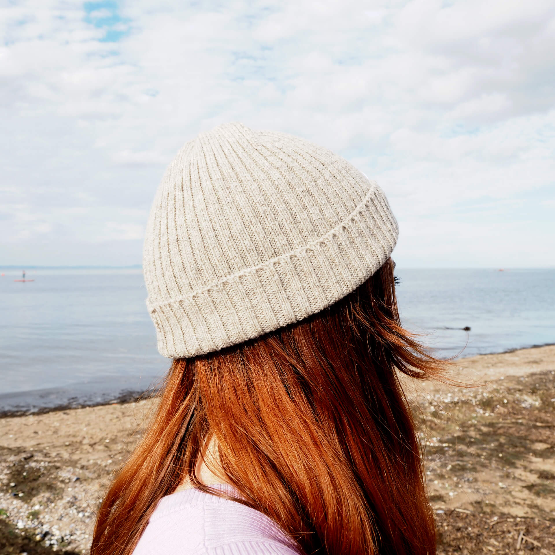 A side view of a woman with red hair, wearing a grey ribbed beanie by K.Moods.