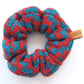 A knitted scrunchie with a thick zig-zag pattern by K.Moods. It is lime blue and red, and is on a white background.