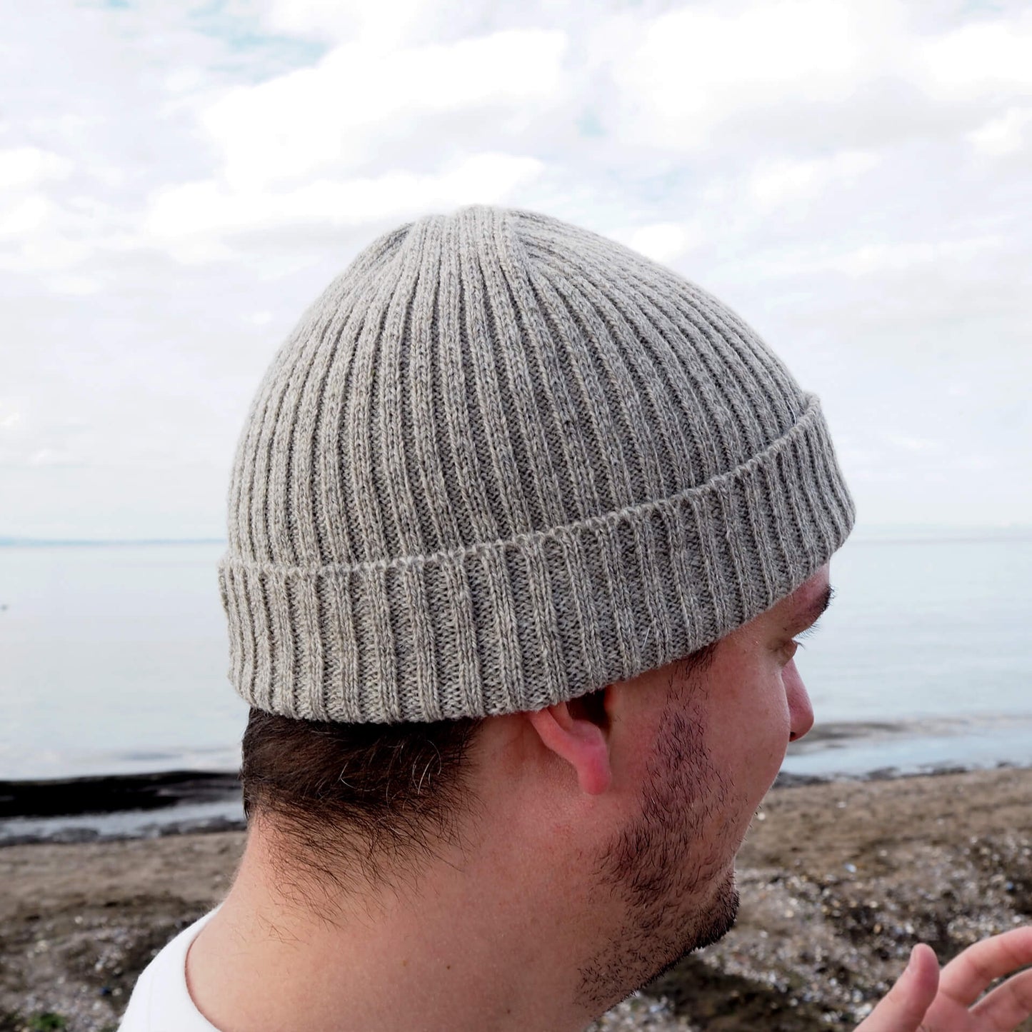 A side view of a man wearing a grey ribbed beanie by K.Moods.