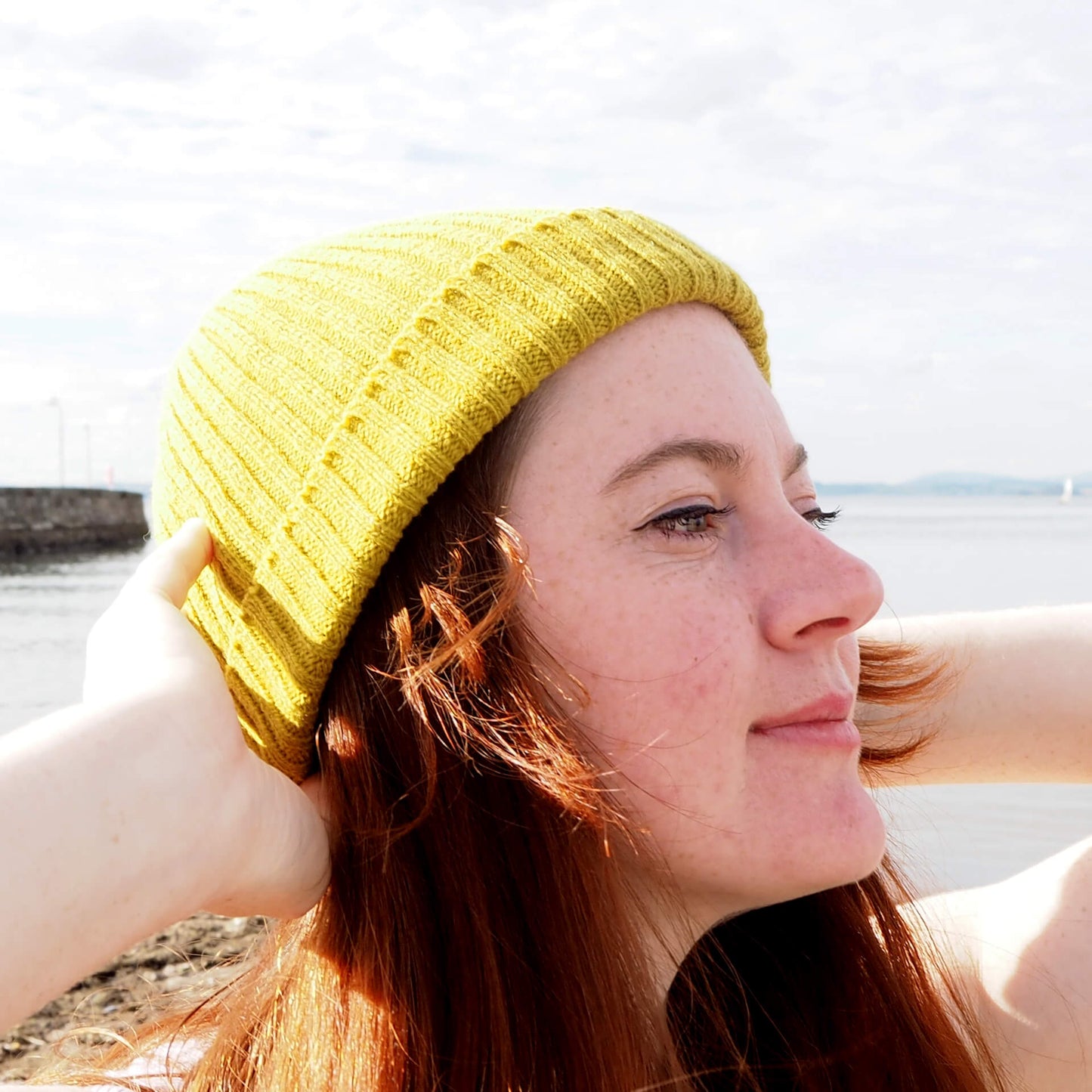A profile of a woman with red hair wears a lime green ribbed beanie by K.Moods.