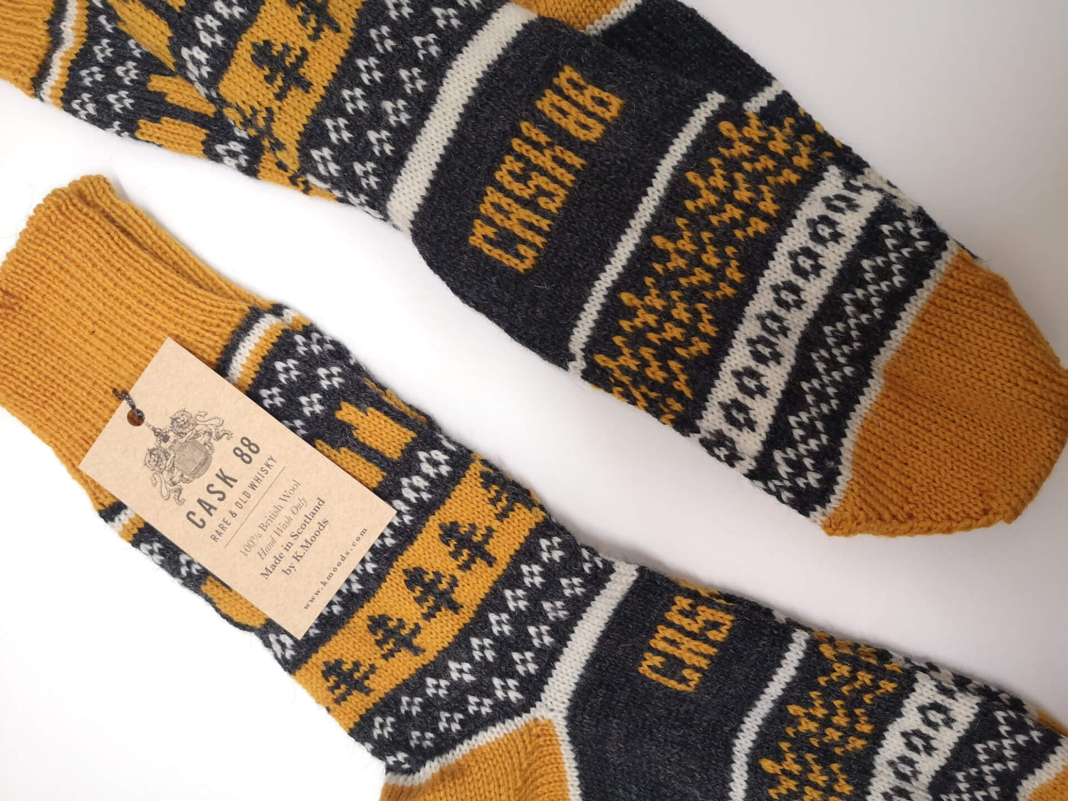 A pair of knitted Fair Isle socks featuring grey, white, and mustard yellow patterns.
